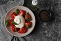 Delicious burrata cheese with tomatoes and basil, oil and peppercorns on grey table, flat lay