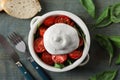 Delicious burrata cheese with tomatoes and basil served on grey wooden table, flat lay