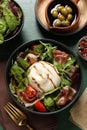 Delicious burrata salad served on green wooden table, flat lay