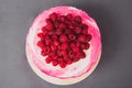 A delicious cake decorated with raspberries on a gray background.