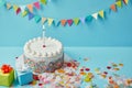 Delicious cake with sugar sprinkles, gifts and confetti on blue background