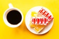 Delicious cakes on a plate and coffee cup, top view. Bright yellow background Royalty Free Stock Photo