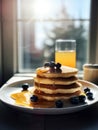 Delicious caloric breakfast of pancakes with honey and blueberries. A stack of fluffy pancakes on white plate near the window. Royalty Free Stock Photo