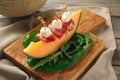 Delicious canape with melon, prosciutto and mozzarella on wooden board