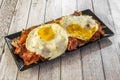 Delicious cap of broken eggs with ham and chips served in a black rectangular plate Royalty Free Stock Photo