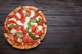 Delicious Caprese pizza with tomatoes, mozzarella and basil on dark wooden table, top view. Space for text