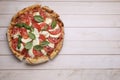 Delicious Caprese pizza with tomatoes, mozzarella and basil on light wooden table, top view. Space for text