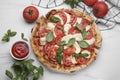 Delicious Caprese pizza with tomatoes, mozzarella and basil served on white marble table, flat lay