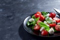 Italian caprese salad with sliced tomatoes, mozzarella cheese, basil, olive oil. Served in black plate with fork over Royalty Free Stock Photo