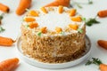 Delicious carrot cake decorated with mastic sweet carrots. Homemade carrot cake with yellow crumbs in the white plate