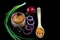 Delicious caviar, roe close up, pike caviar in a transparent jar, wooden spoon purple onion cut into rings on a black background,