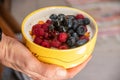 Delicious ceramic yellow bowl with fresh berries (raspberries and blackberries) and cereals Royalty Free Stock Photo