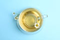 Delicious chamomile tea in glass cup on blue background, top view Royalty Free Stock Photo