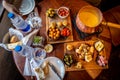 Delicious cheese fondue with dips, pickles, olives, pork, croutons, sausage and cherry tomatoes seen from above