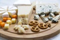 Delicious cheeses: camembert, blue cheese, brie, parmesan, mimolette and edam with pretzels and walnuts on round wooden board. Royalty Free Stock Photo