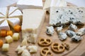 Delicious cheeses: camembert, blue cheese, brie, parmesan, mimolette and edam with pretzels and walnuts on round wooden board. Royalty Free Stock Photo