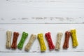 Delicious chewing colored bones for dogs with different tastes on white wooden background