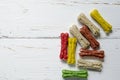 Delicious chewing colored bones for dogs with different tastes on white wooden background