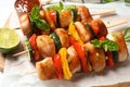 Delicious chicken shish kebabs with vegetables and lime on wooden board, closeup Royalty Free Stock Photo