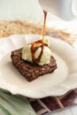 Delicious chocolate brownie with ice cream and caramel syrup falling