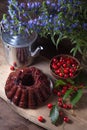 Delicious chocolate cake with berry of sweet cherry, vintage kettle and bouquet of blue flowers on dark wooden background Royalty Free Stock Photo