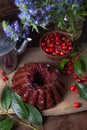 Delicious chocolate cake with berry of sweet cherry, vintage kettle and bouquet of blue flowers on dark wooden background Royalty Free Stock Photo