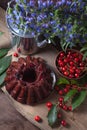 Delicious chocolate cake with berry of sweet cherry, vintage kettle and bouquet of blue flowers on dark wooden background Royalty Free Stock Photo