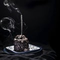 Delicious chocolate cake with a blowed gray colored candle on it on a black background, isolated, close up Royalty Free Stock Photo