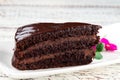 Delicious chocolate cake on white plate and flower on wooden table Royalty Free Stock Photo