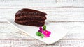 Delicious chocolate cake on white plate and flower on wooden table Royalty Free Stock Photo