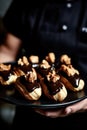Delicious chocolate eclairs with walnuts on a plate held by a chef Royalty Free Stock Photo