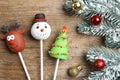 Delicious Christmas themed cake pops and fir tree branches with balls on wooden table, flat lay Royalty Free Stock Photo