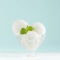 Delicious classic creamy ice cream scoops in glass ice-cream bowl with green mint in modern mint color interior on white wood.