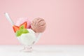 Delicious classic various flavor creamy ice cream scoops in bowl with strawberry slices, spoon, mint in modern pink color interior Royalty Free Stock Photo
