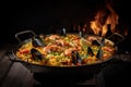 Delicious close up shot of traditional Spanish Paella on iron pan with fireplace as background