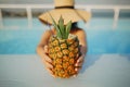 Delicious cocktail in pineapple. Summer vacation. Beautiful young woman in hat relaxing in pool with drink. Girl enjoying warm Royalty Free Stock Photo