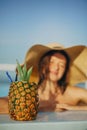 Delicious cocktail in pineapple. Summer vacation. Beautiful young woman in hat relaxing in pool with drink. Girl enjoying warm Royalty Free Stock Photo