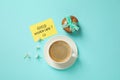 Delicious coffee, cookies, flowers and card with GOOD MORNING wish on blue background, flat lay