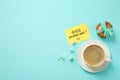 Delicious coffee, cookies, flowers and card with GOOD MORNING wish on light blue background, flat lay. Space for text