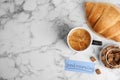 Delicious coffee, croissant and card with words GOOD MORNING on white table, flat lay. Space for text Royalty Free Stock Photo