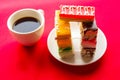 Delicious color cakes on a plate and coffee cup. Bright red background Royalty Free Stock Photo