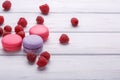 Delicious colorful biscuits macaroons with raspberries over white wooden background. space for text