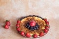 A delicious and colorful cheesecake decorated with strawberries, blueberries, and plum on a marble table