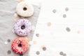 Delicious colorful donuts with sprinkles on stylish white table with confetti, flat lay, copy space. Party concept. No diet. Candy