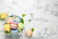 Delicious colorful macarons and flowers on white marble table, flat lay. Space for text Royalty Free Stock Photo