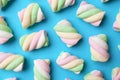 Delicious colorful marshmallows on light blue background, flat lay