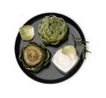 Delicious cooked artichokes with tasty sauce and rosemary isolated on white, top view