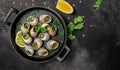 Delicious cooked sea escargo snails with herbs, butter, garlic on metal plate on a dark background. gourmet food. Restaurant menu