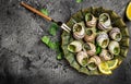 Delicious cooked sea escargo snails with herbs, butter, garlic on metal plate with forks. wine glass. gourmet food. Restaurant Royalty Free Stock Photo