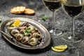 Delicious cooked sea escargo snails with herbs, butter, garlic on metal plate with forks. wine glass. gourmet food. Restaurant Royalty Free Stock Photo